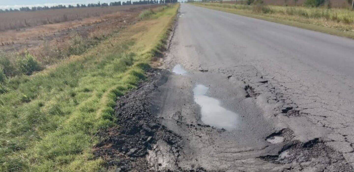 Estado deteriorado de una carretera rural con baches y charcos de agua