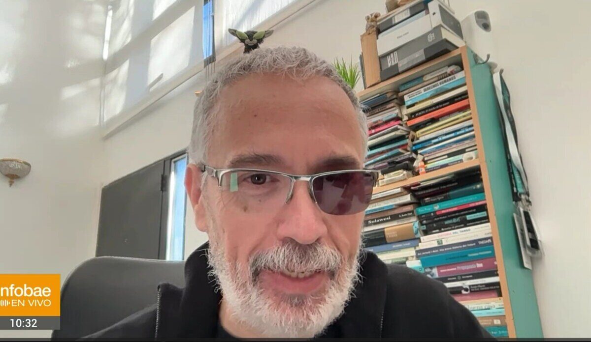 Hombre con gafas y barba en un entorno de oficina con estanterías llenas de libros
