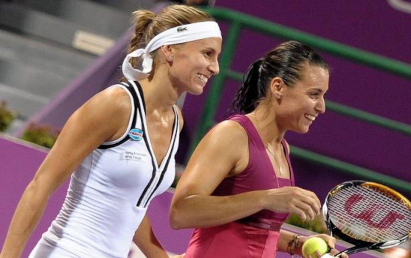 Gisela Dulko y Flavia Pennetta sonríen mientras caminan juntas con raquetas de tenis
