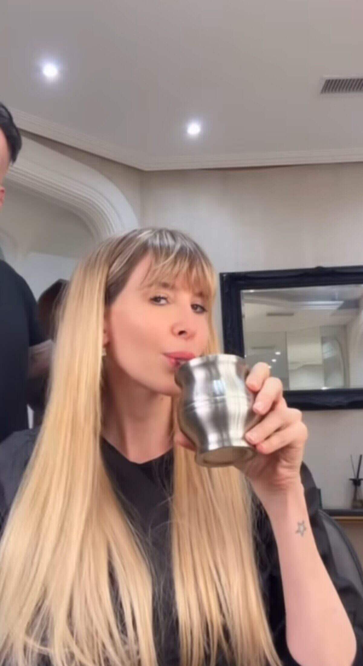 Guillermina Valdés con cabello largo y lacio, sosteniendo un vaso en un salón de belleza