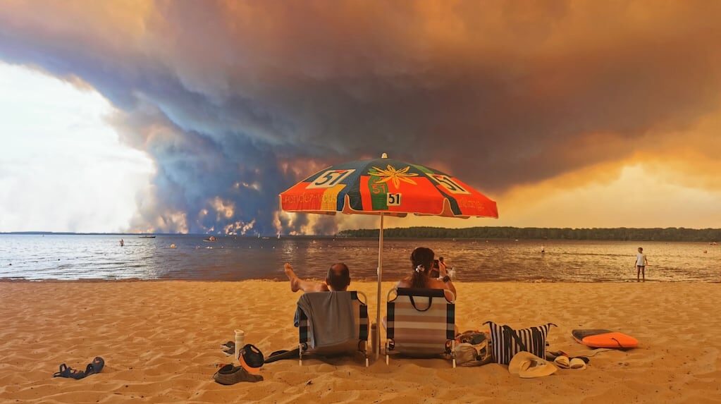 Pareja en la playa con incendios de fondo en Francia