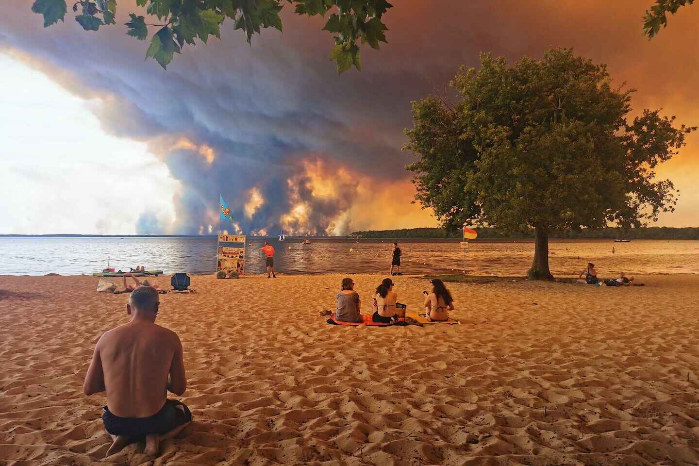Pareja en la playa con incendios forestales al fondo en Francia