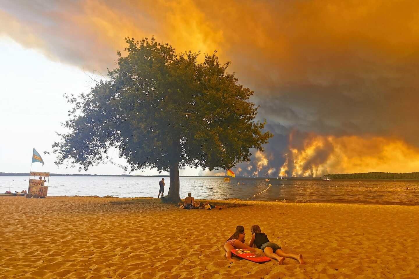 Pareja en la playa con incendios forestales al fondo en Francia
