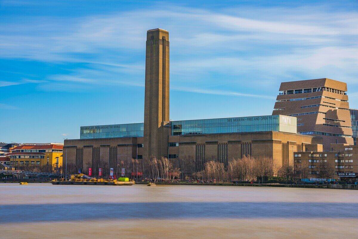 Vista del museo Tate Modern en Londres con su icónica chimenea y el río Támesis en primer plano
