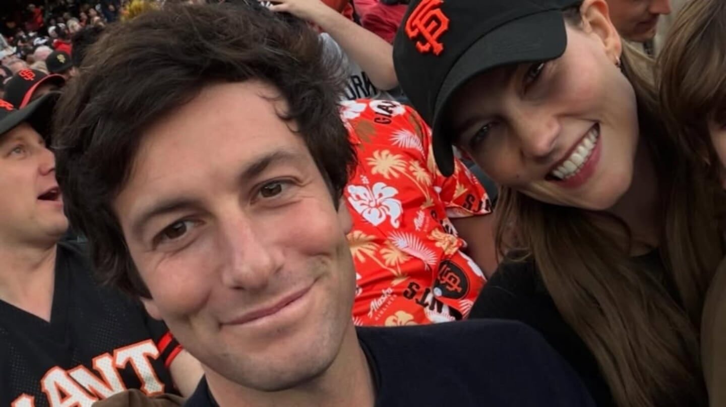Joshua Kushner sonriendo en un evento deportivo con una mujer a su lado