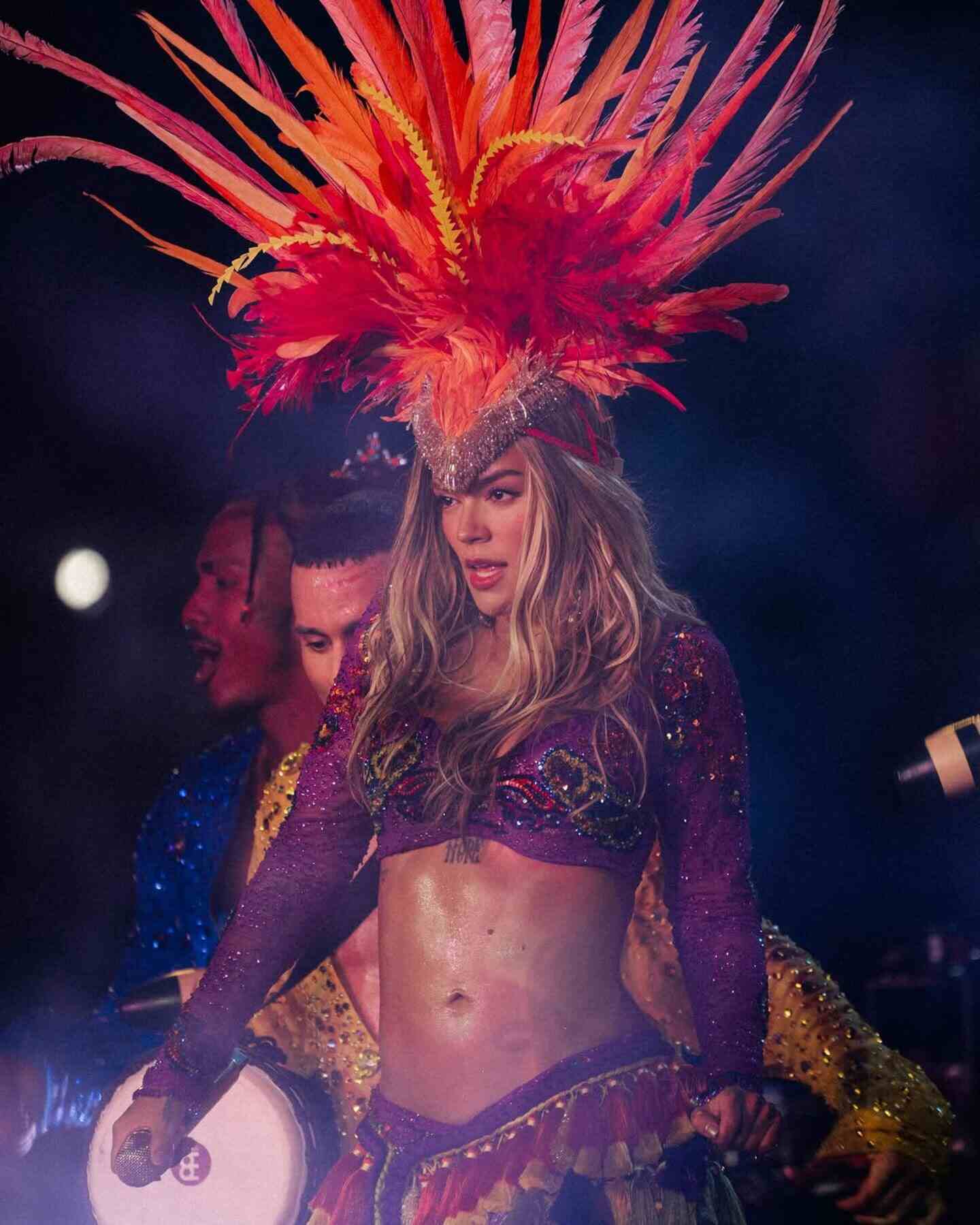 Karol G en concierto en Chicago con un atuendo colorido y plumas brillantes