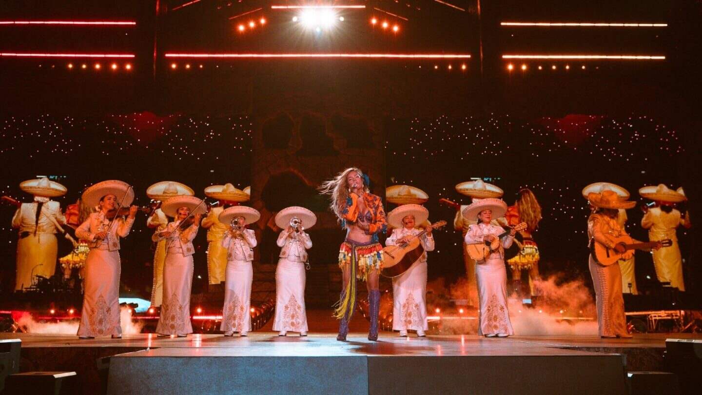Karol G actuando en un escenario con un grupo de músicos vestidos de mariachi en Toronto