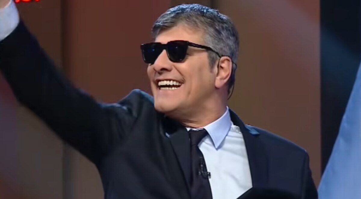 Mario Pergolini sonriendo y saludando con gafas de sol en un escenario