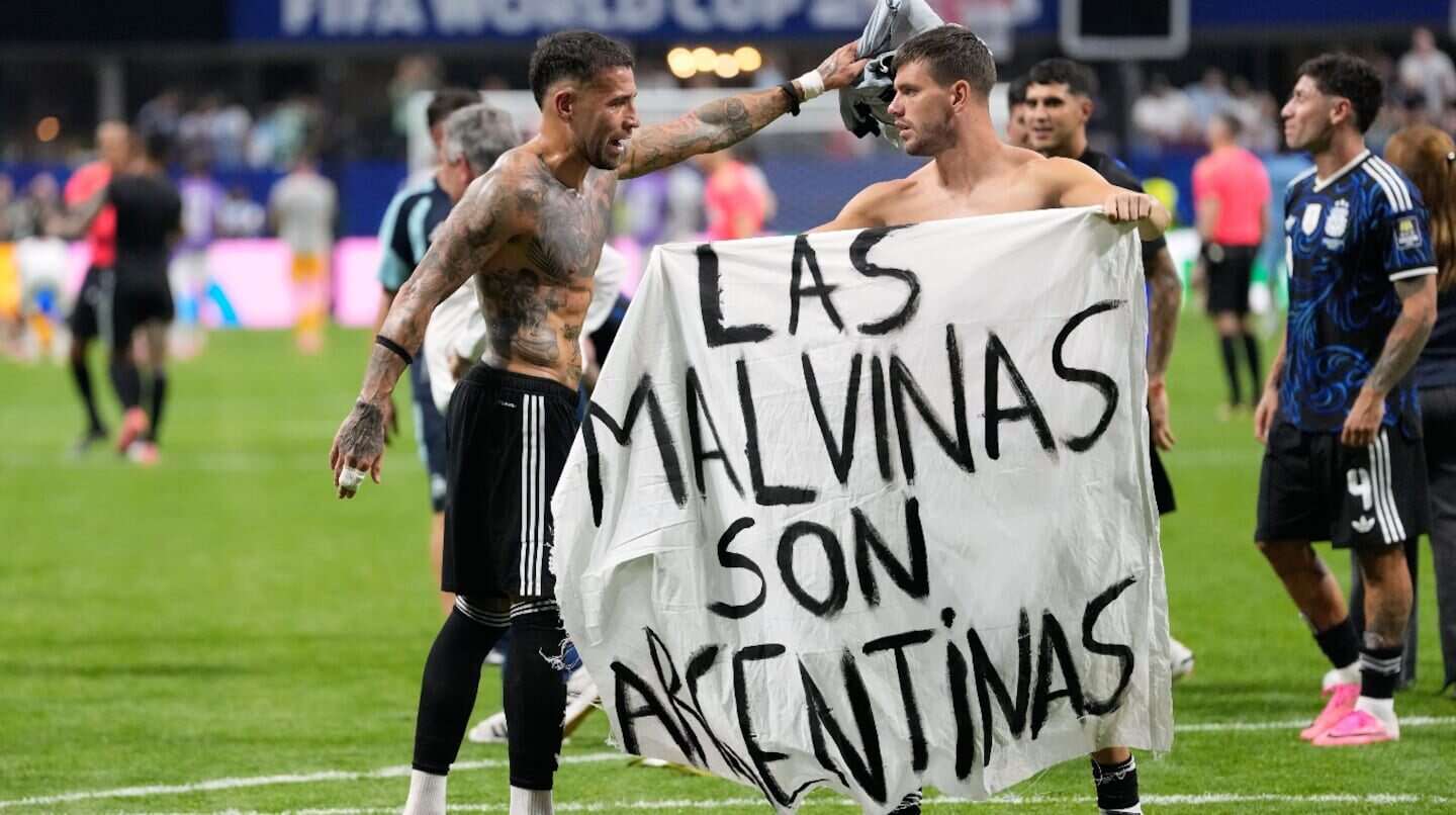 Jugadores de la Selección argentina sosteniendo una bandera que dice 'Las Malvinas son argentinas' en un partido