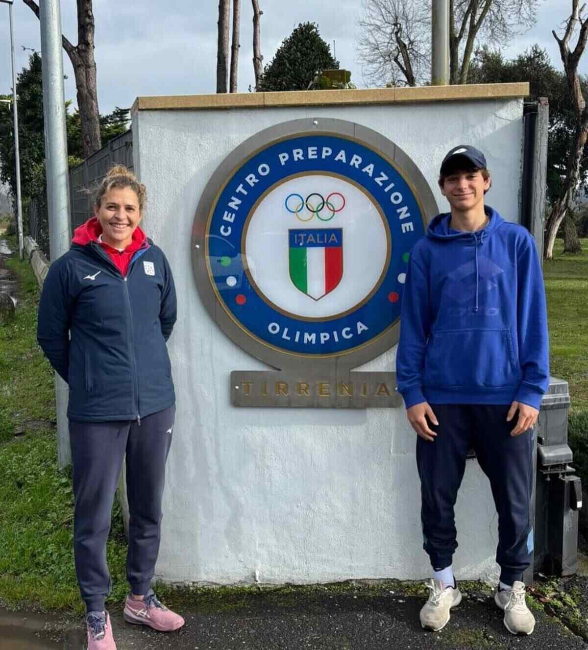 Carla Lucero junto a un joven tenista frente al Centro Preparación Olímpica en Italia