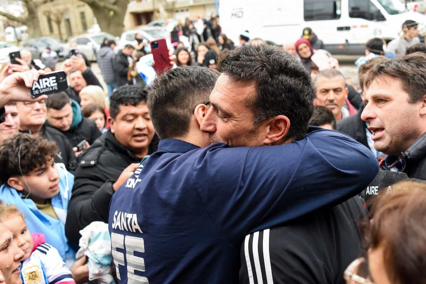 Dos hombres se abrazan en medio de una multitud en la pastelería de Corina Scaloni en Pujato