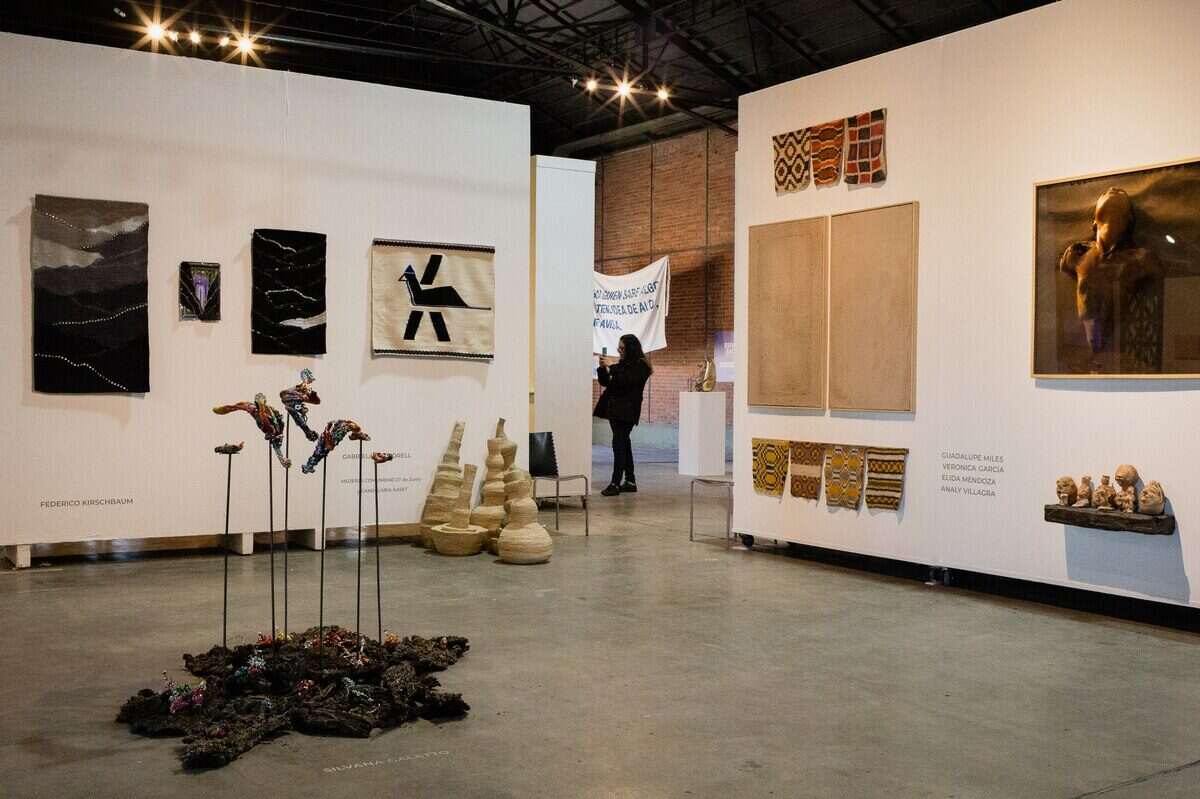 Exposición de arte contemporáneo en la MicroFeria de Rosario con obras en las paredes y esculturas en el centro