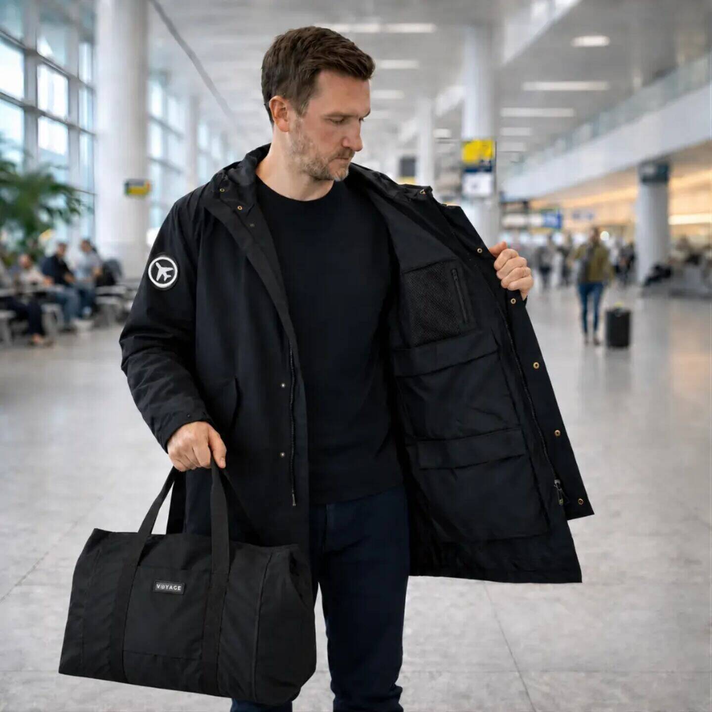 Hombre en un aeropuerto usando una campera Voyage Coat con compartimientos visibles