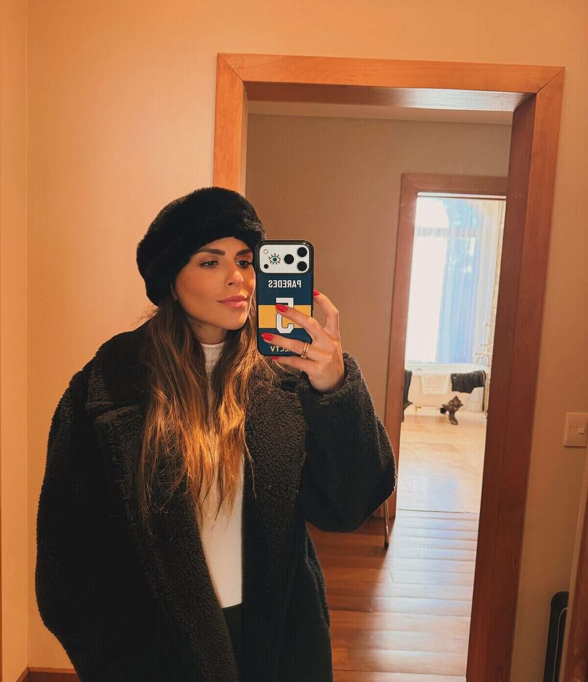 Mujer con abrigo negro y gorro en un espejo