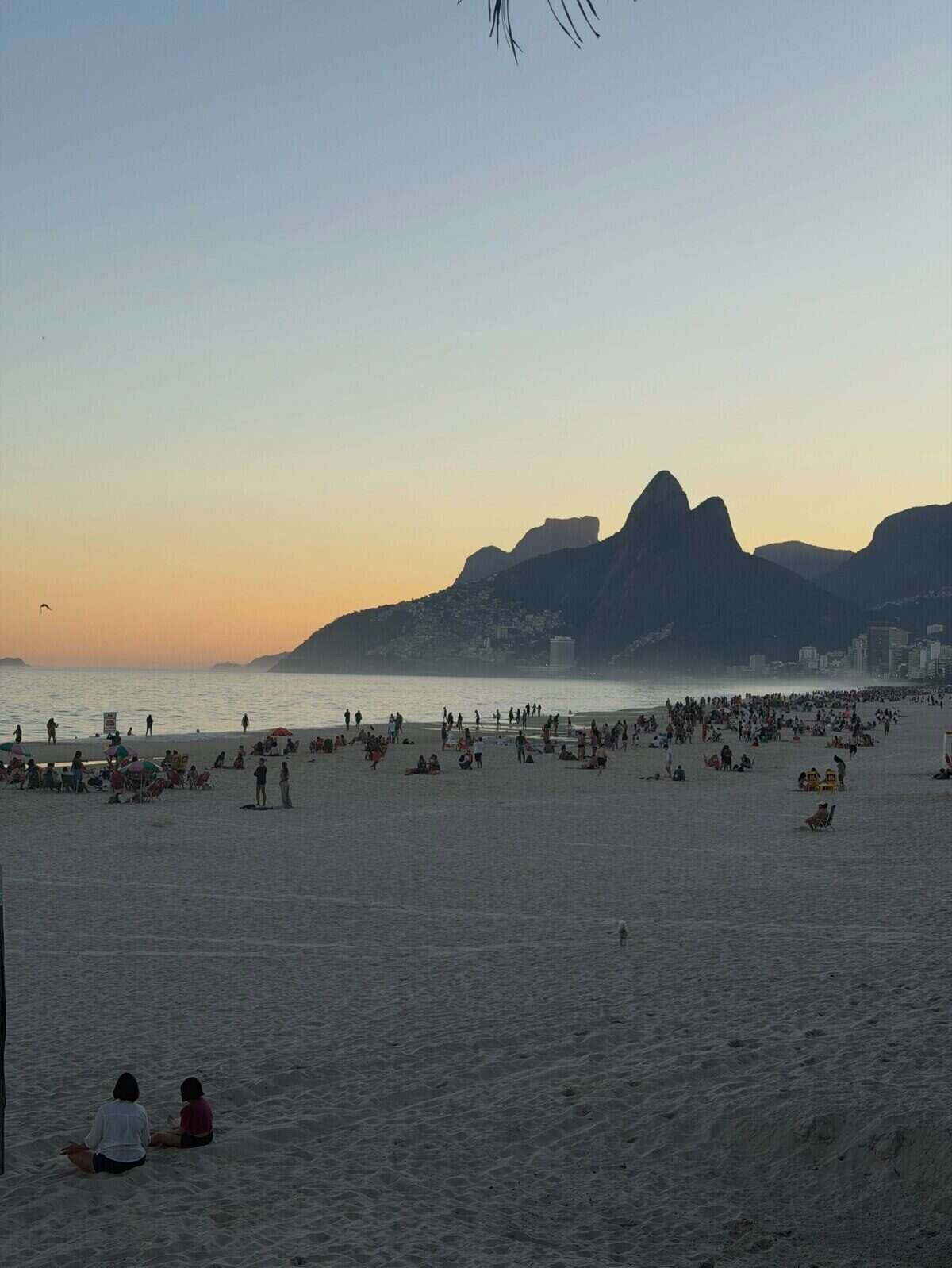 Atardecer en la playa de Río de Janeiro con personas disfrutando de la arena y el mar