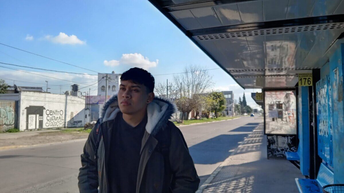 Joven esperando en una parada de autobús en un barrio popular