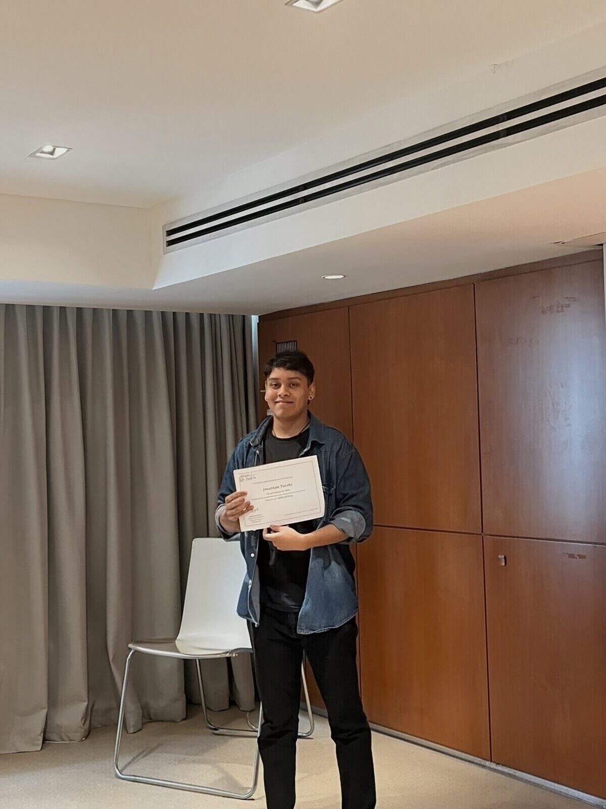 Joven sosteniendo un certificado en un entorno formal