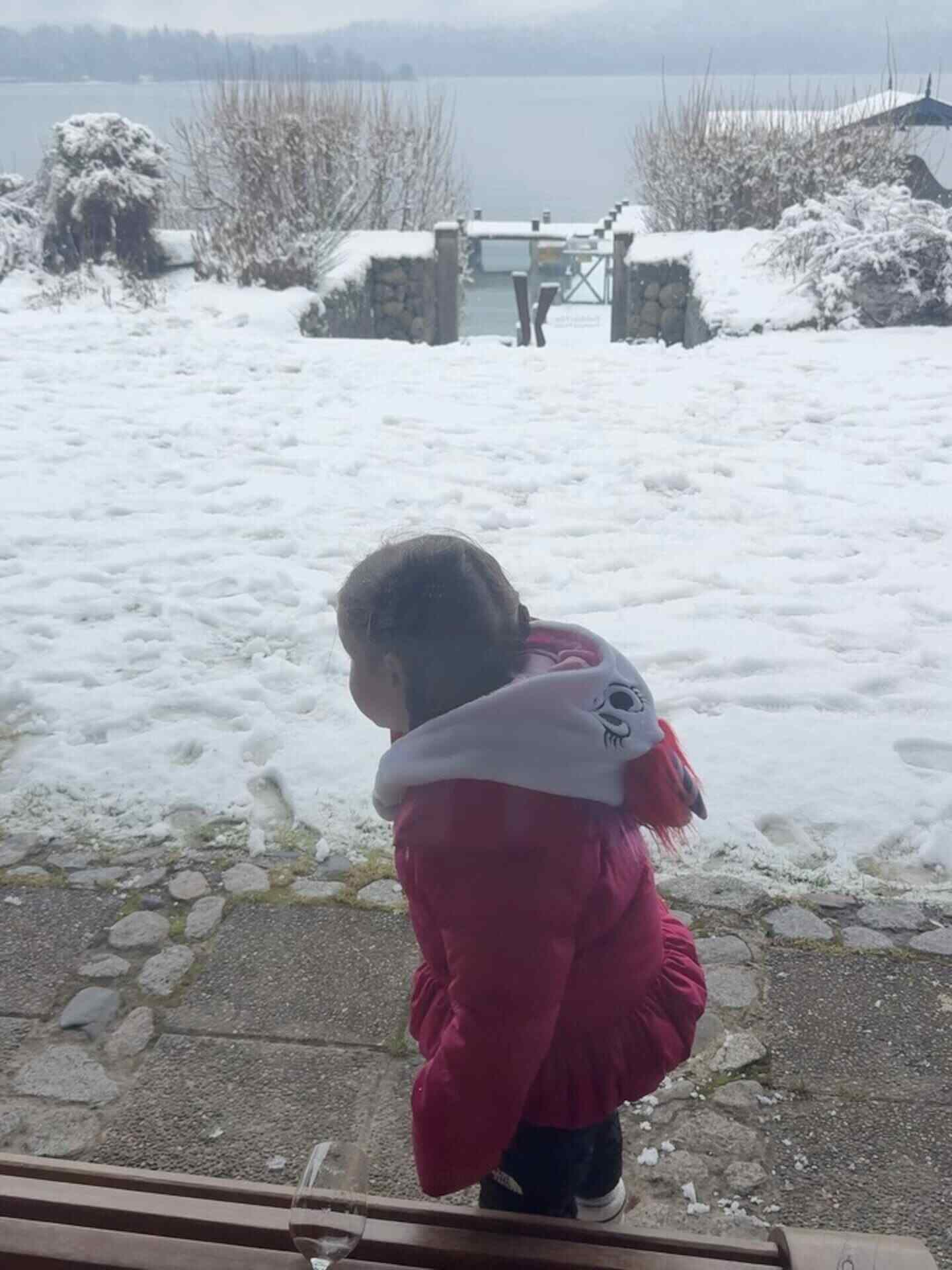 Niña con abrigo rosa observa la nieve en la Patagonia