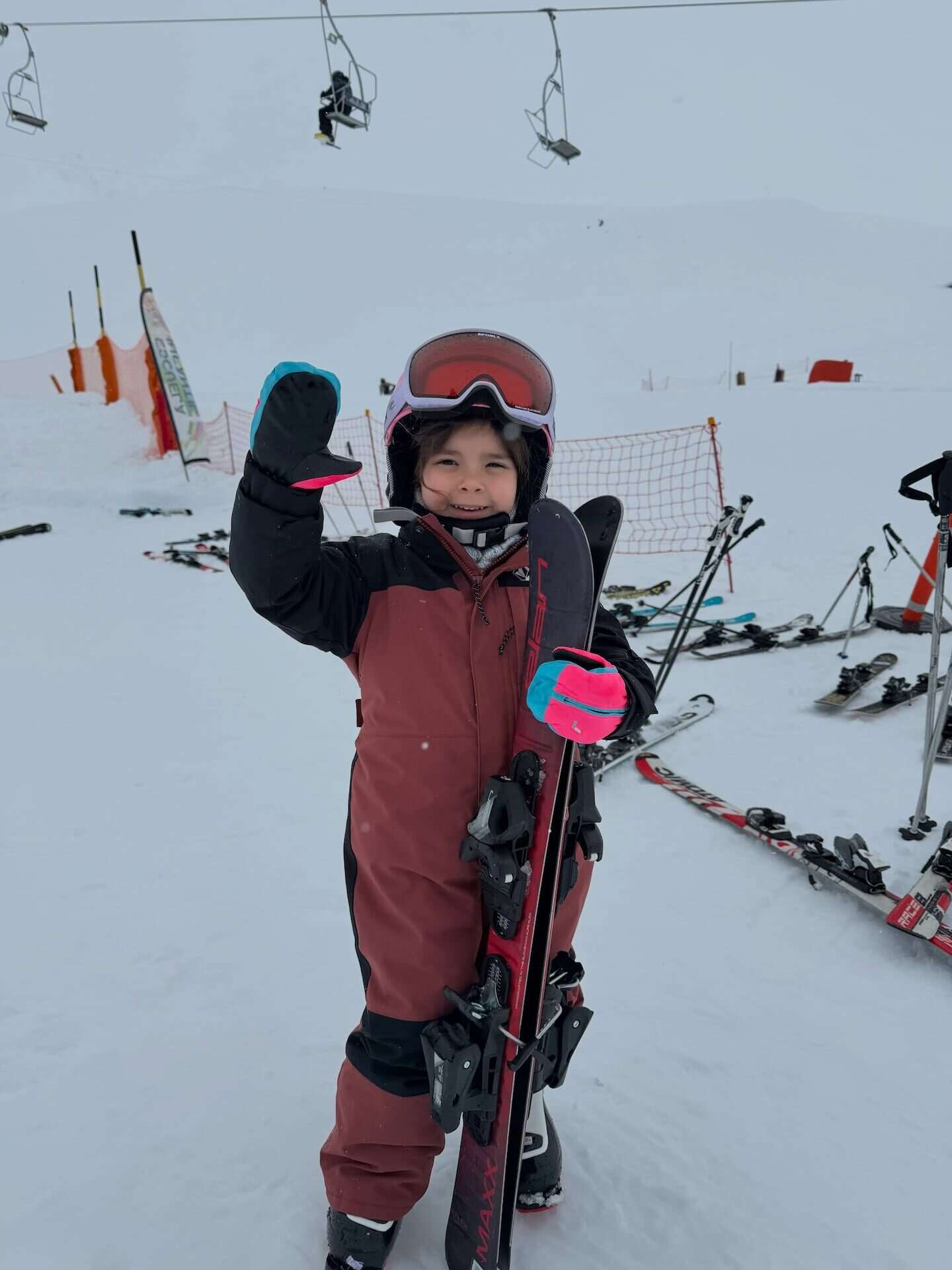 Niña sonriente con equipo de esquí en la nieve