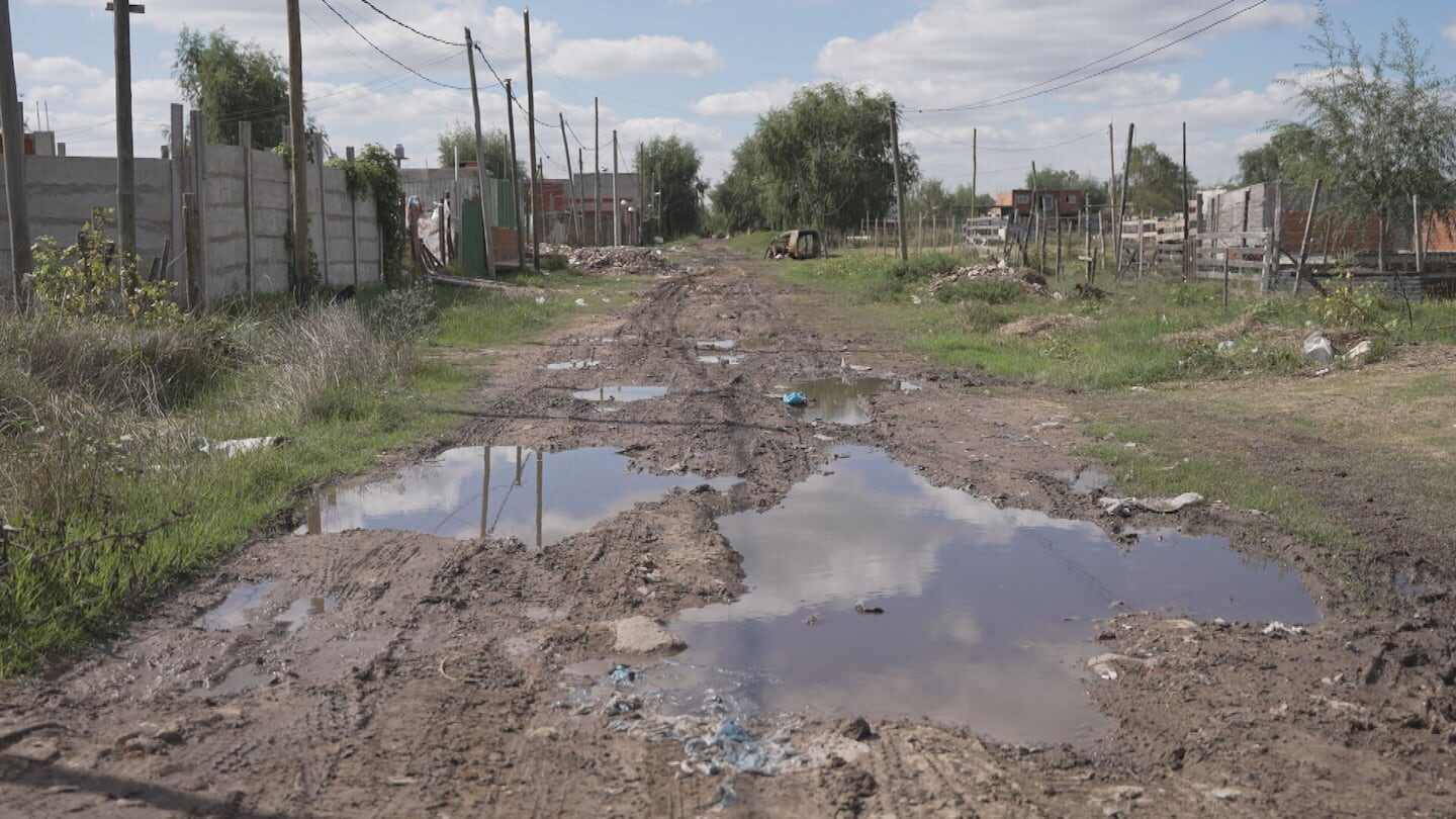 Camino de tierra con charcos de agua en un asentamiento en Argentina