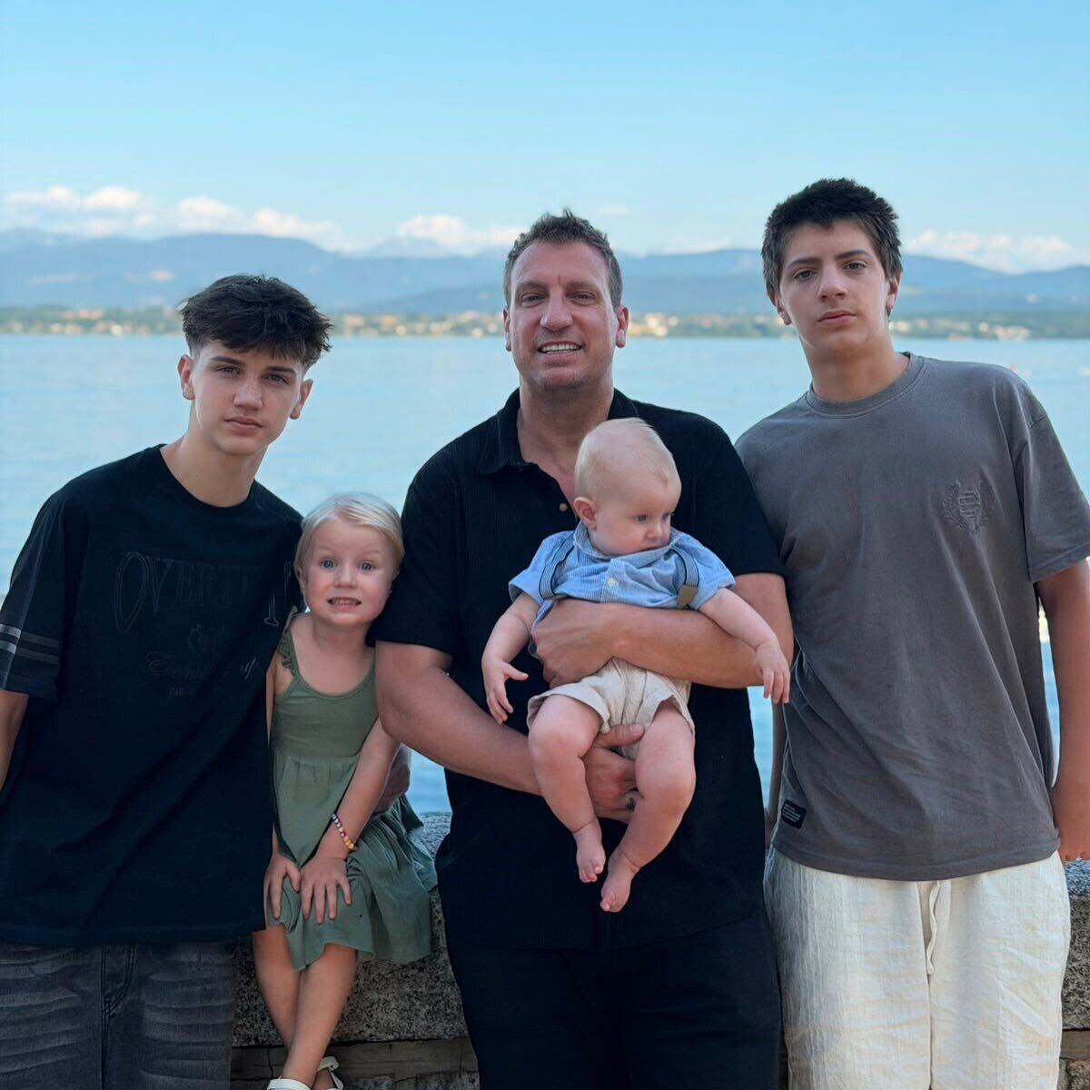 Maxi López sosteniendo a su hijo pequeño, acompañado de sus otros tres hijos en un paisaje suizo