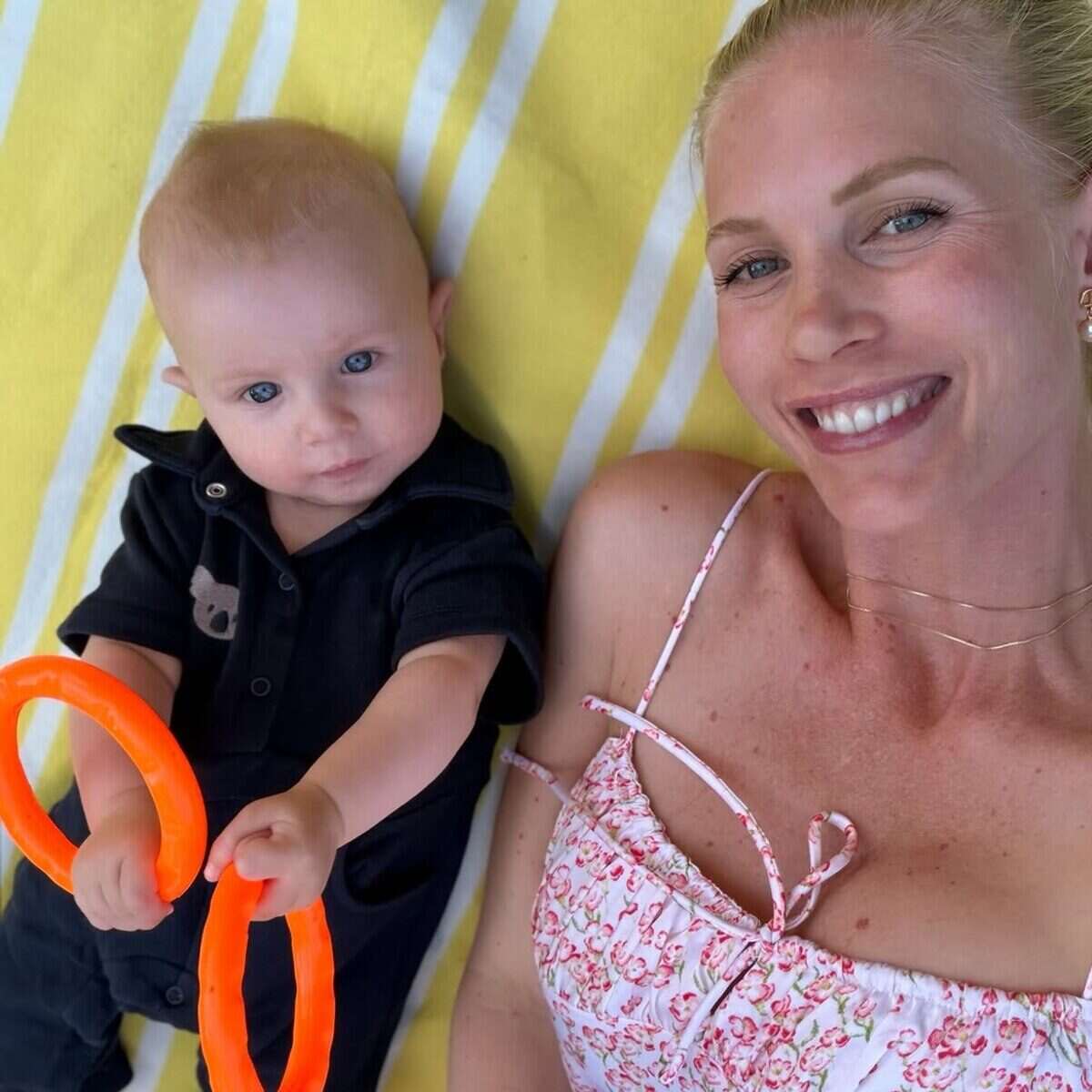 Daniela Christiansson sonríe junto a su hijo en una manta amarilla en Suiza