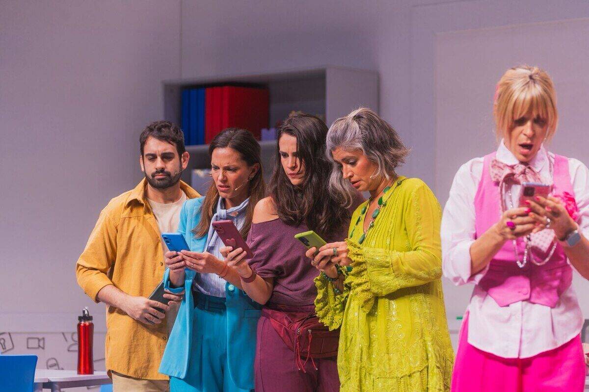 Mica Riera y el elenco revisando sus teléfonos en el escenario de 'El Chat de Mamis'