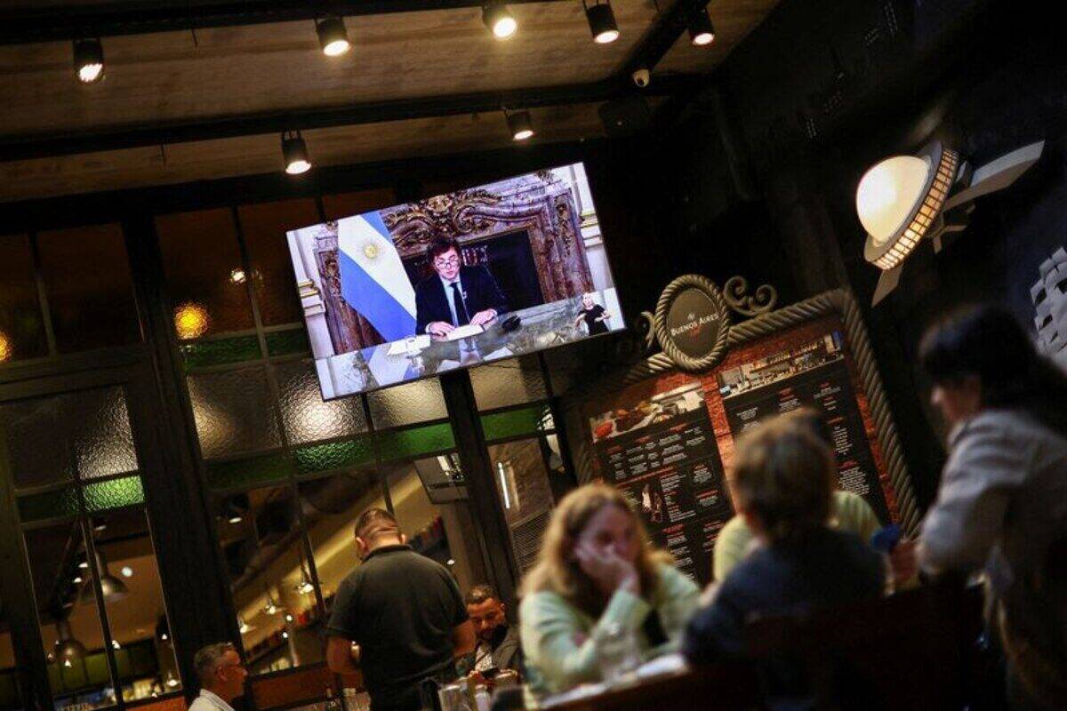Javier Milei presentando su reforma a la Carta Orgánica del BCRA en una pantalla en un restaurante