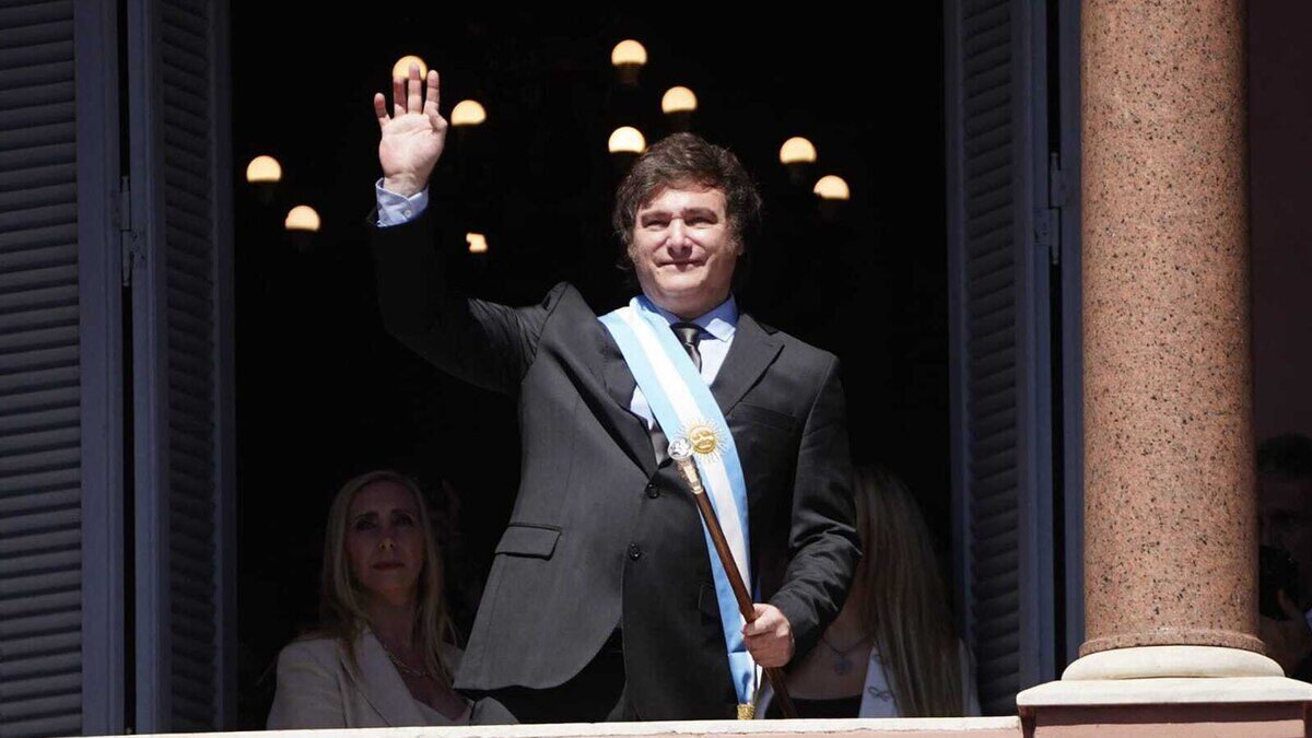 Javier Milei saluda desde un balcón con una banda presidencial en un evento oficial