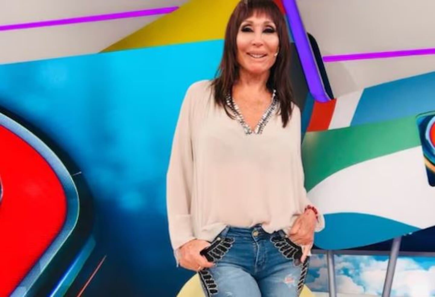 Moria Casán en el set de Intrusos, luciendo una blusa clara y jeans decorados