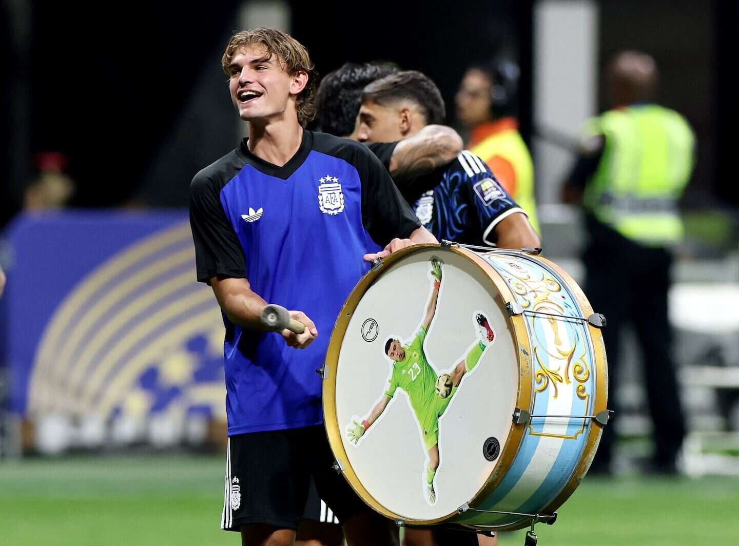 Nico Paz sonríe mientras sostiene un tambor con la imagen de Lionel Messi