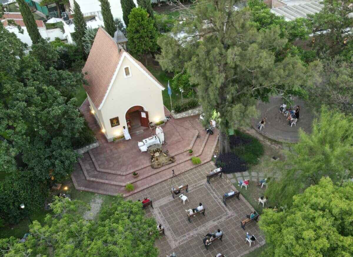 Vista aérea de una iglesia rodeada de árboles y personas sentadas en un parque