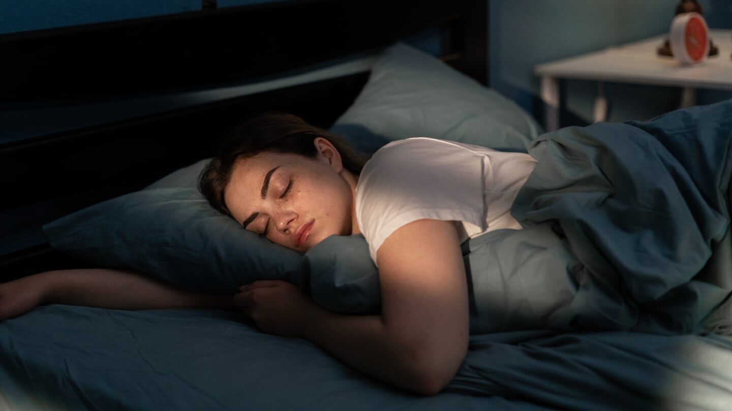 Mujer durmiendo en una cama con sábanas azules