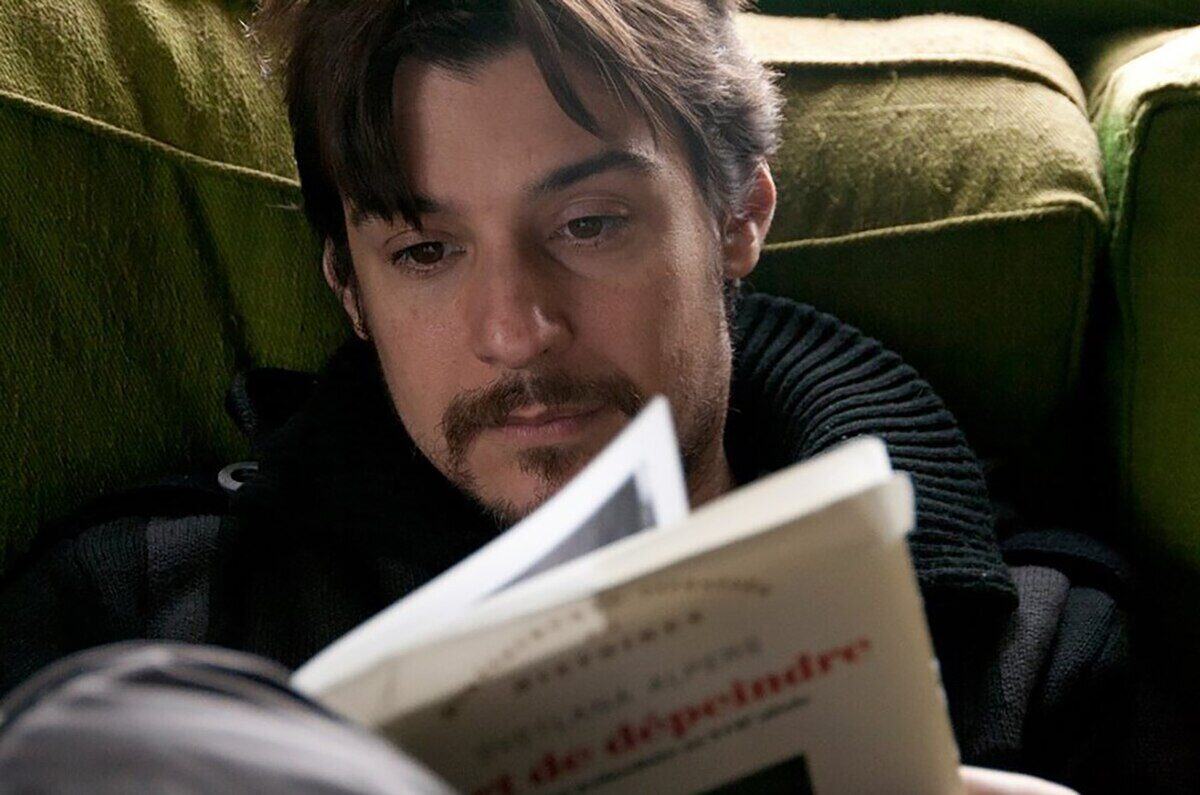 Hombre leyendo un libro en un sofá verde