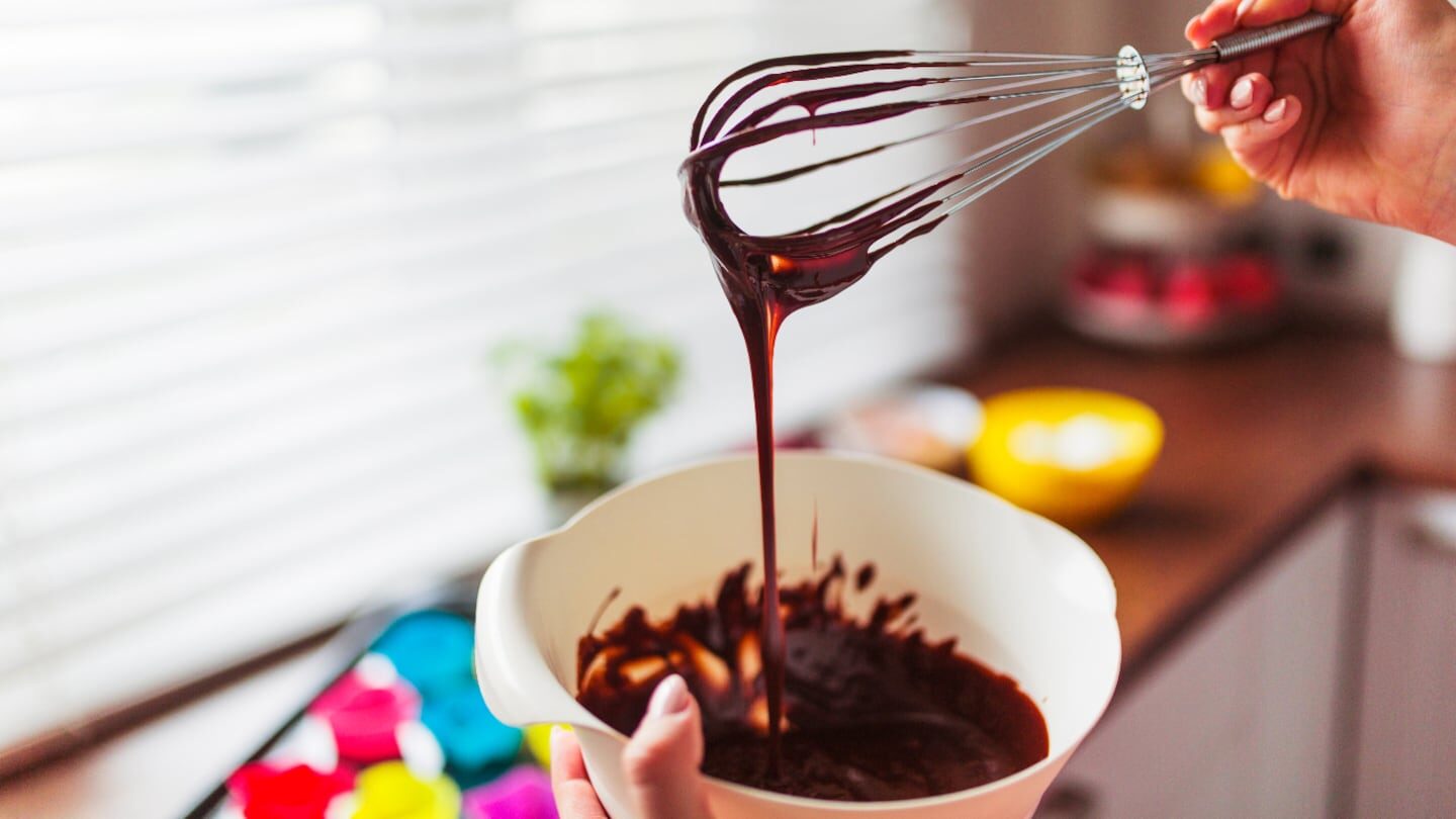 Masa de chocolate siendo batida con un batidor en un tazón blanco