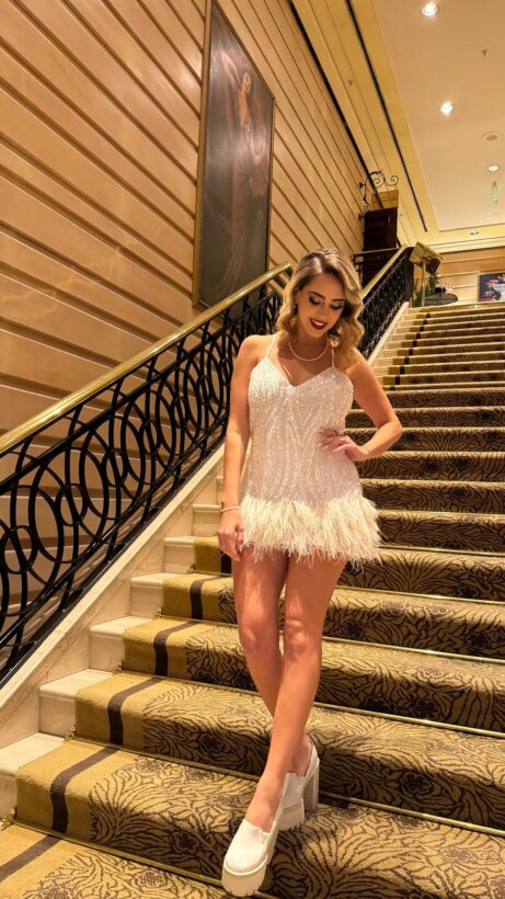 Sabrina Cortez posando en una escalera con un vestido blanco brillante