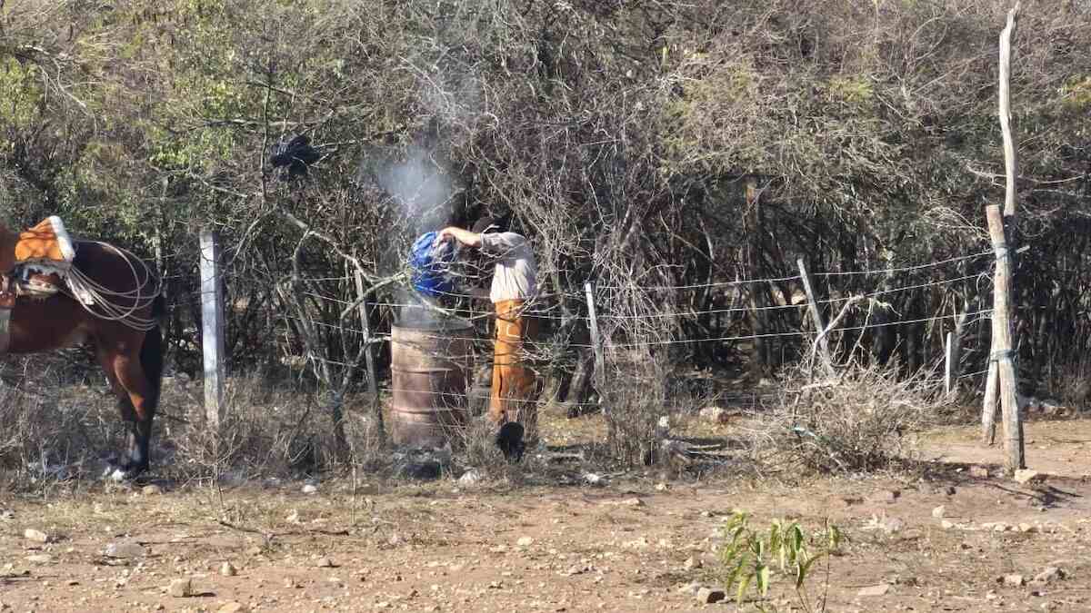 Persona manipulando un barril humeante en un área rural de Salta