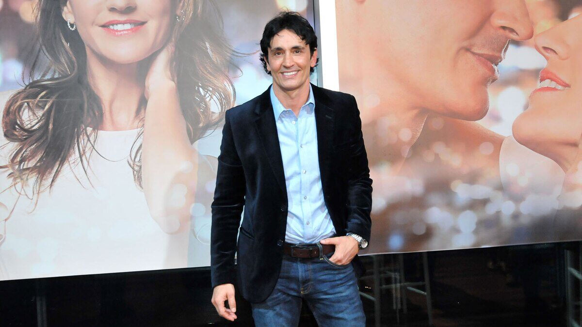Sebastián Estevanez posando en un evento con fondo de carteles de su carrera actoral