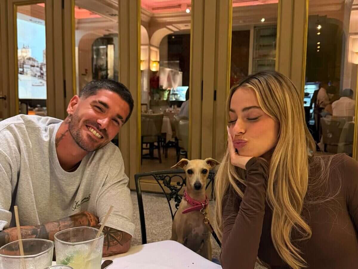 Tini Stoessel y Rodrigo De Paul sonríen en una mesa de restaurante con un perro