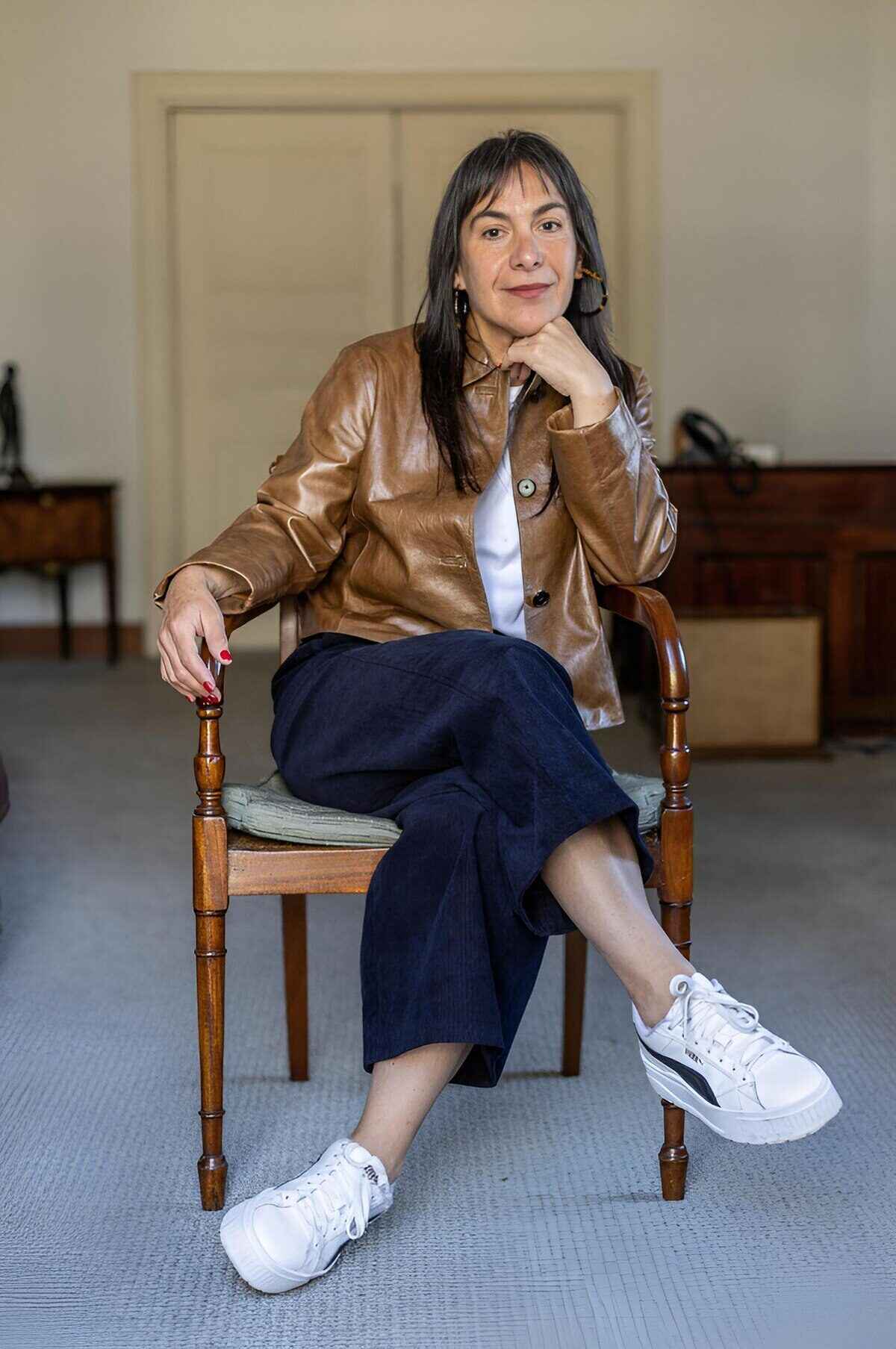 Tania Candiani sentada en una silla con chaqueta de cuero en un ambiente interior