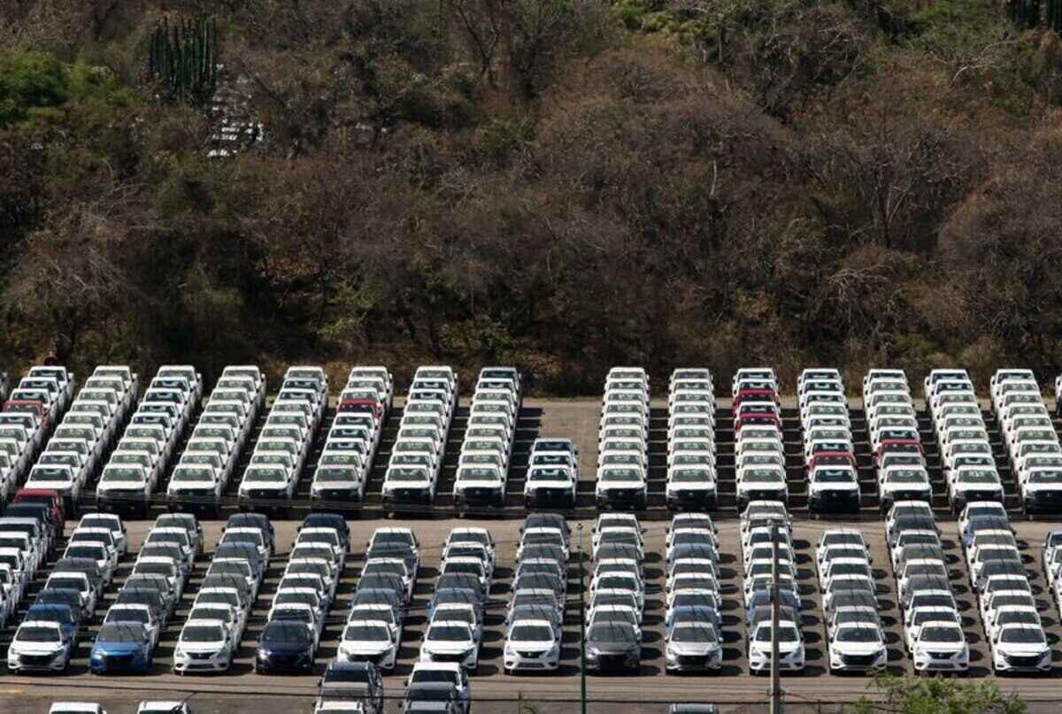 Estacionamiento con numerosos vehículos nuevos en fila en un área industrial