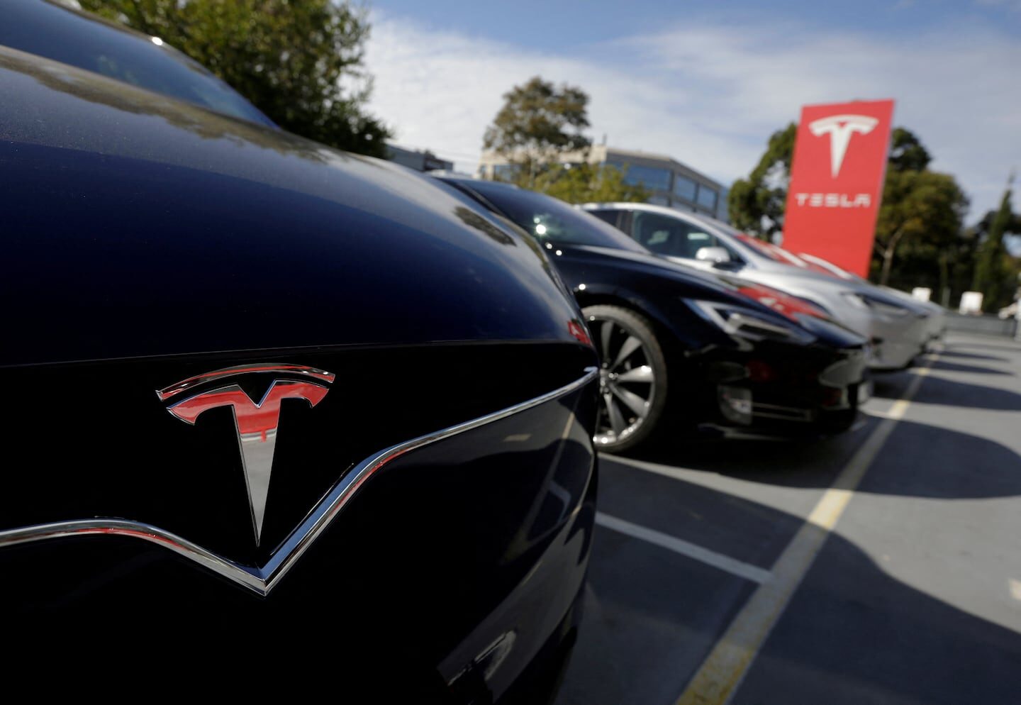 Logotipo de Tesla en un vehículo eléctrico en un estacionamiento