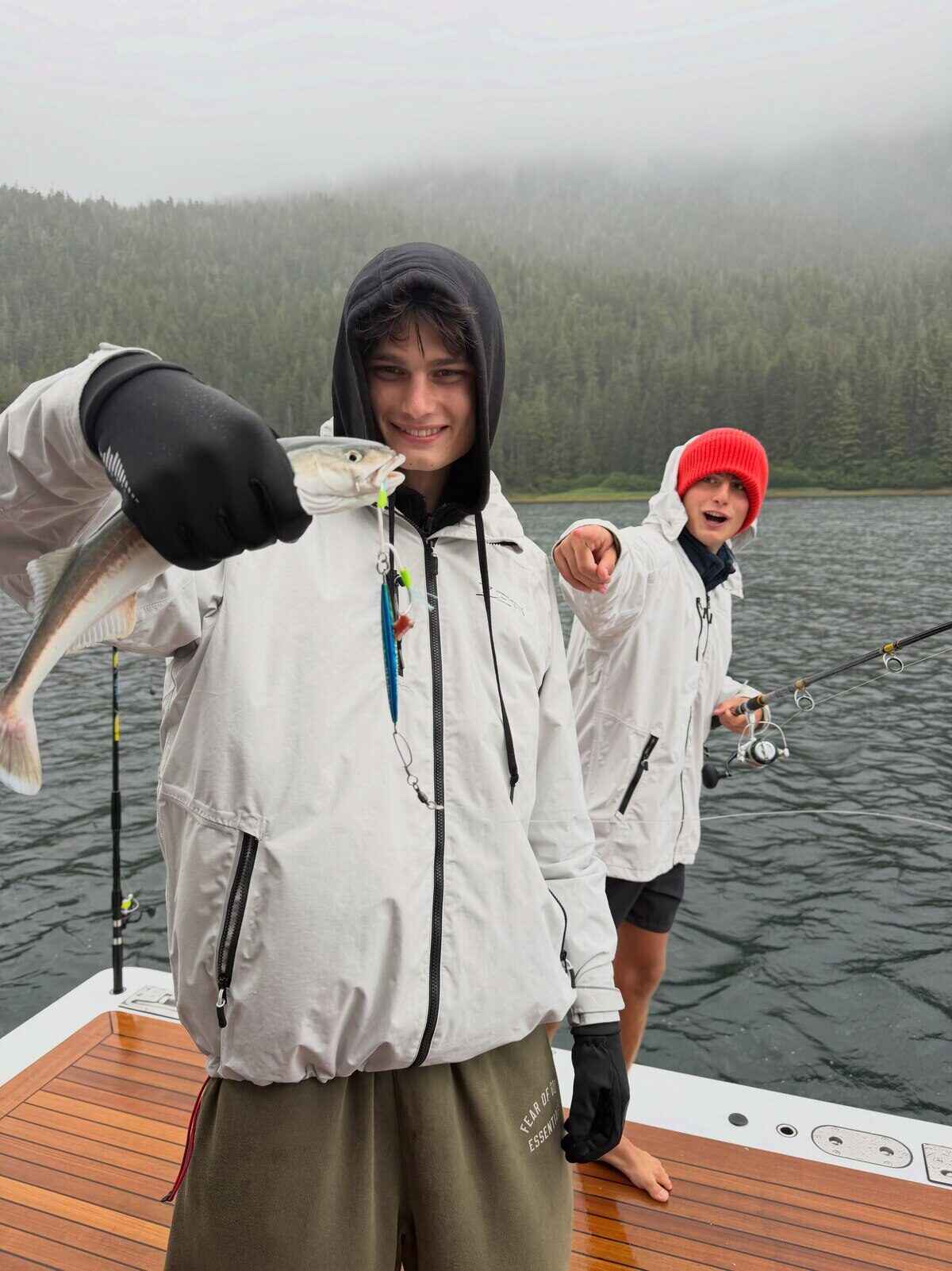 Dos jóvenes pescadores sosteniendo un pez en un bote en Alaska