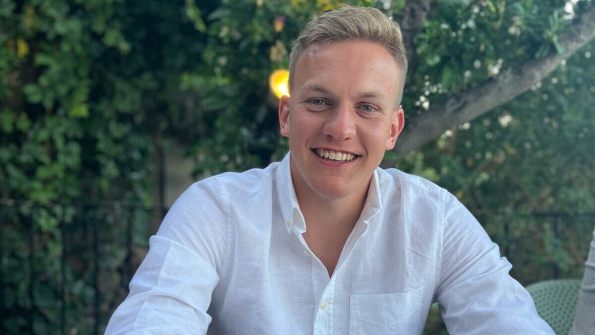 Joven sonriente con camisa blanca en un entorno natural