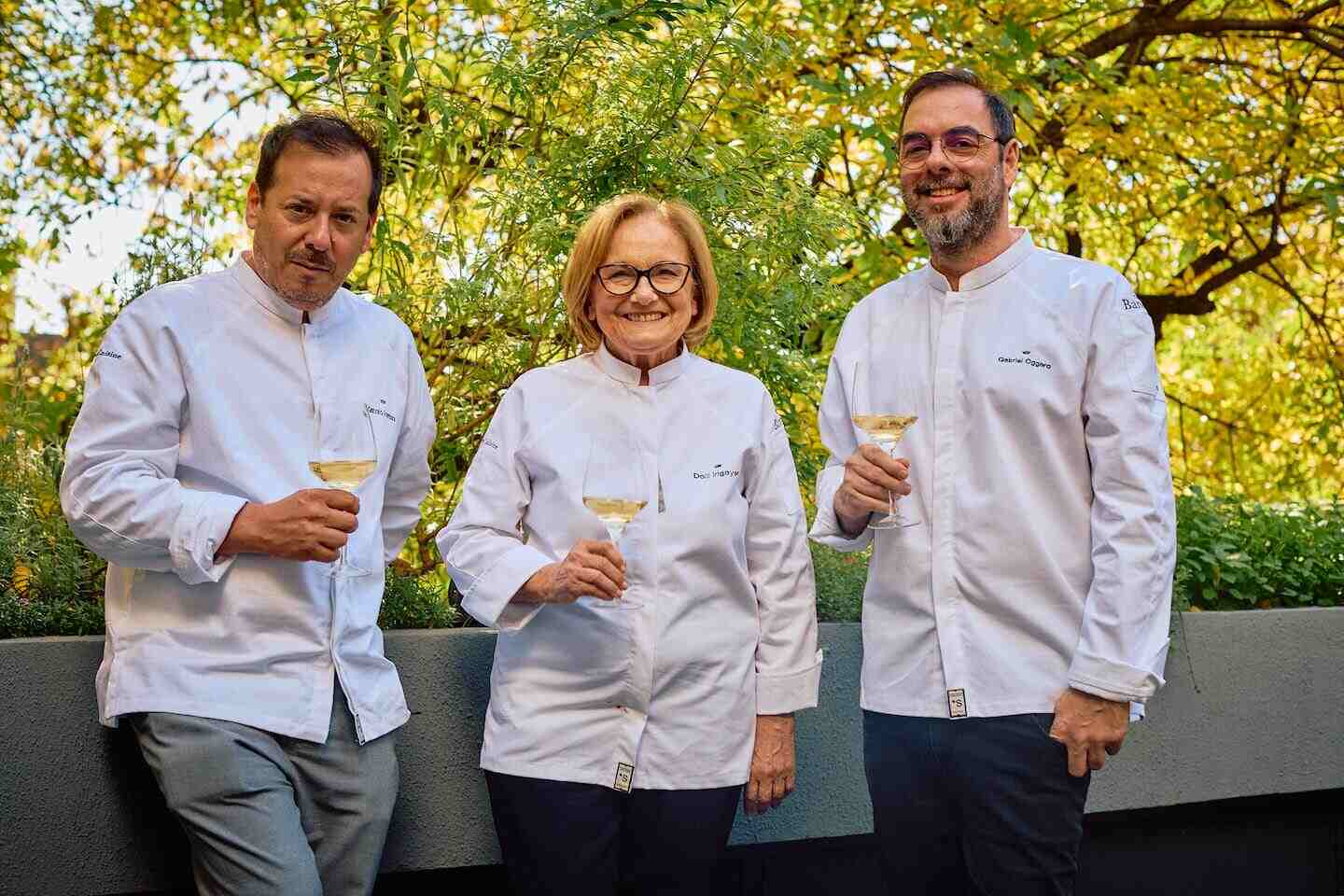 Tres chefs argentinos sosteniendo copas en un entorno natural