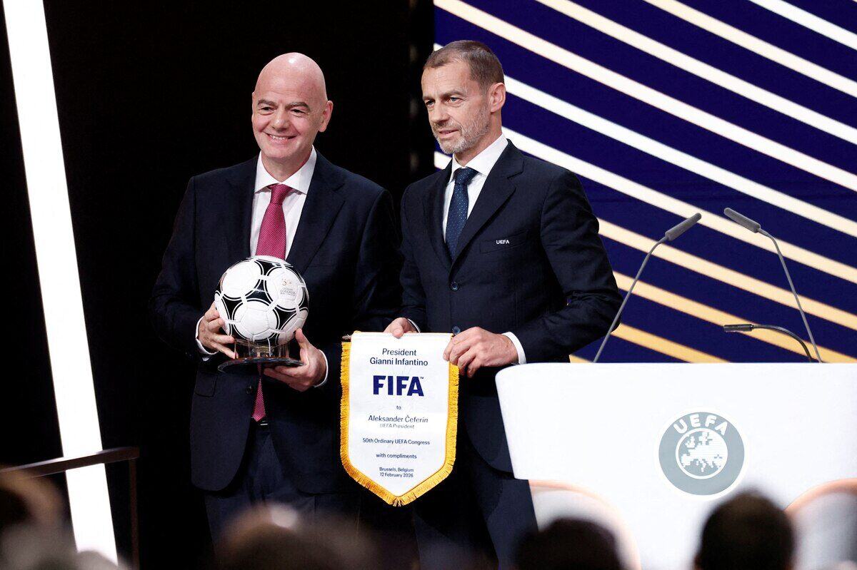 Gianni Infantino y Aleksander Čeferin posan con un balón de fútbol y un estandarte de la UEFA