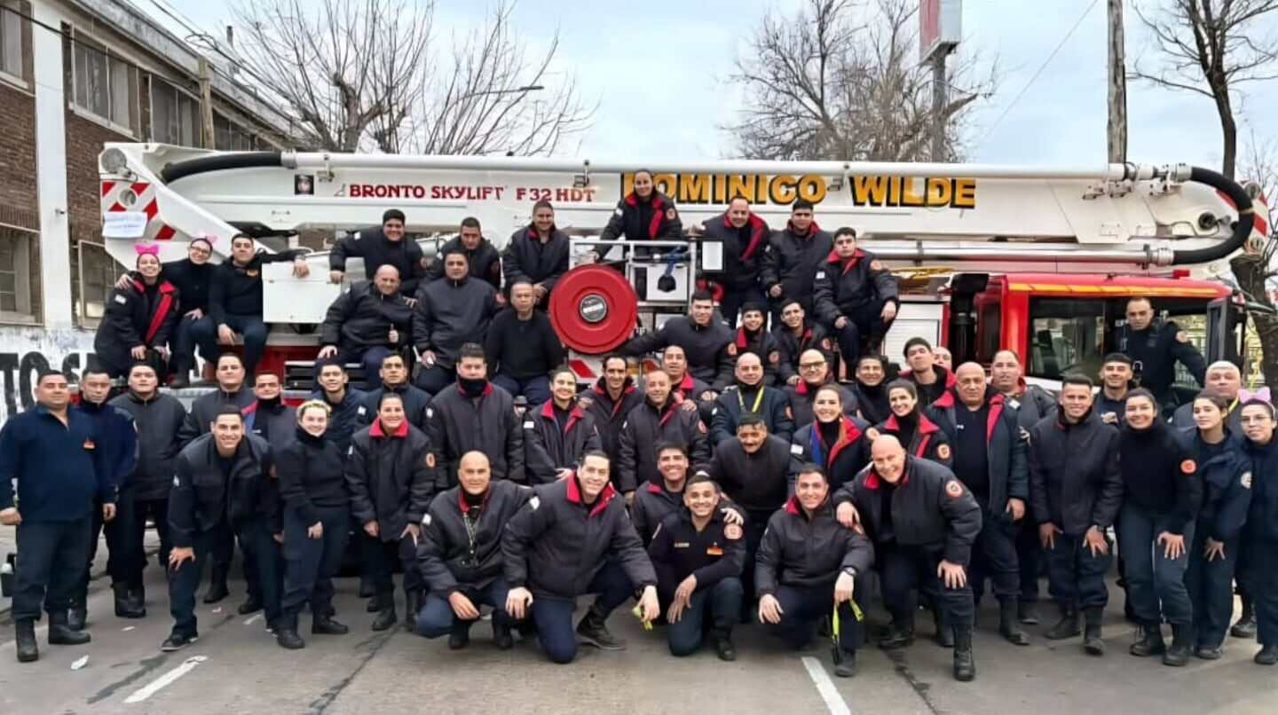 Grupo de bomberos posando frente a un camión de bomberos en Wilde