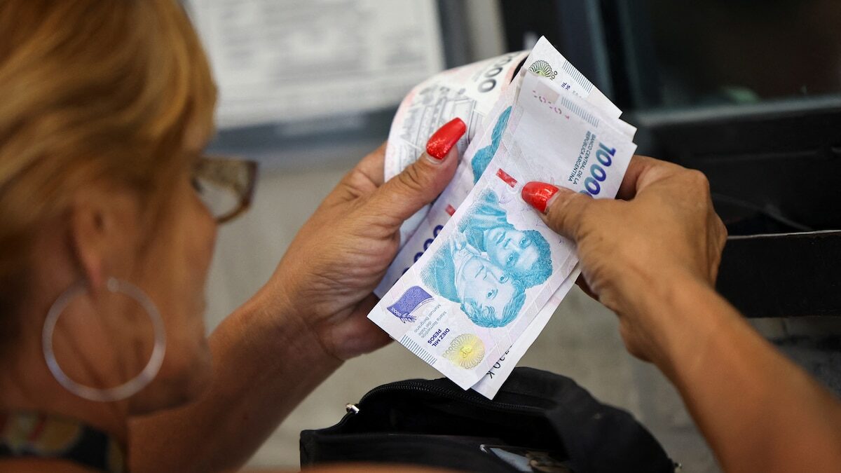 Mujer contando billetes de 1000 pesos argentinos en un banco