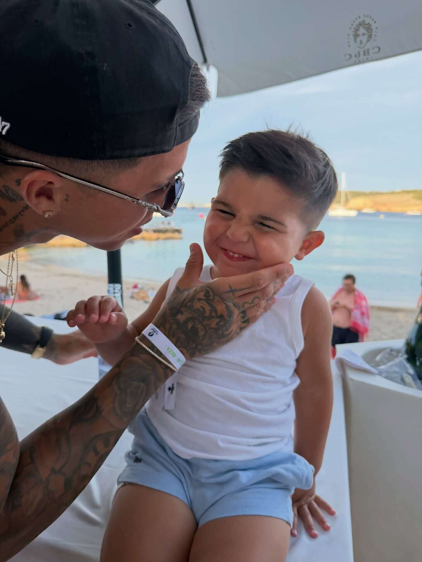 Hombre con tatuajes juega con un niño en la playa de Ibiza