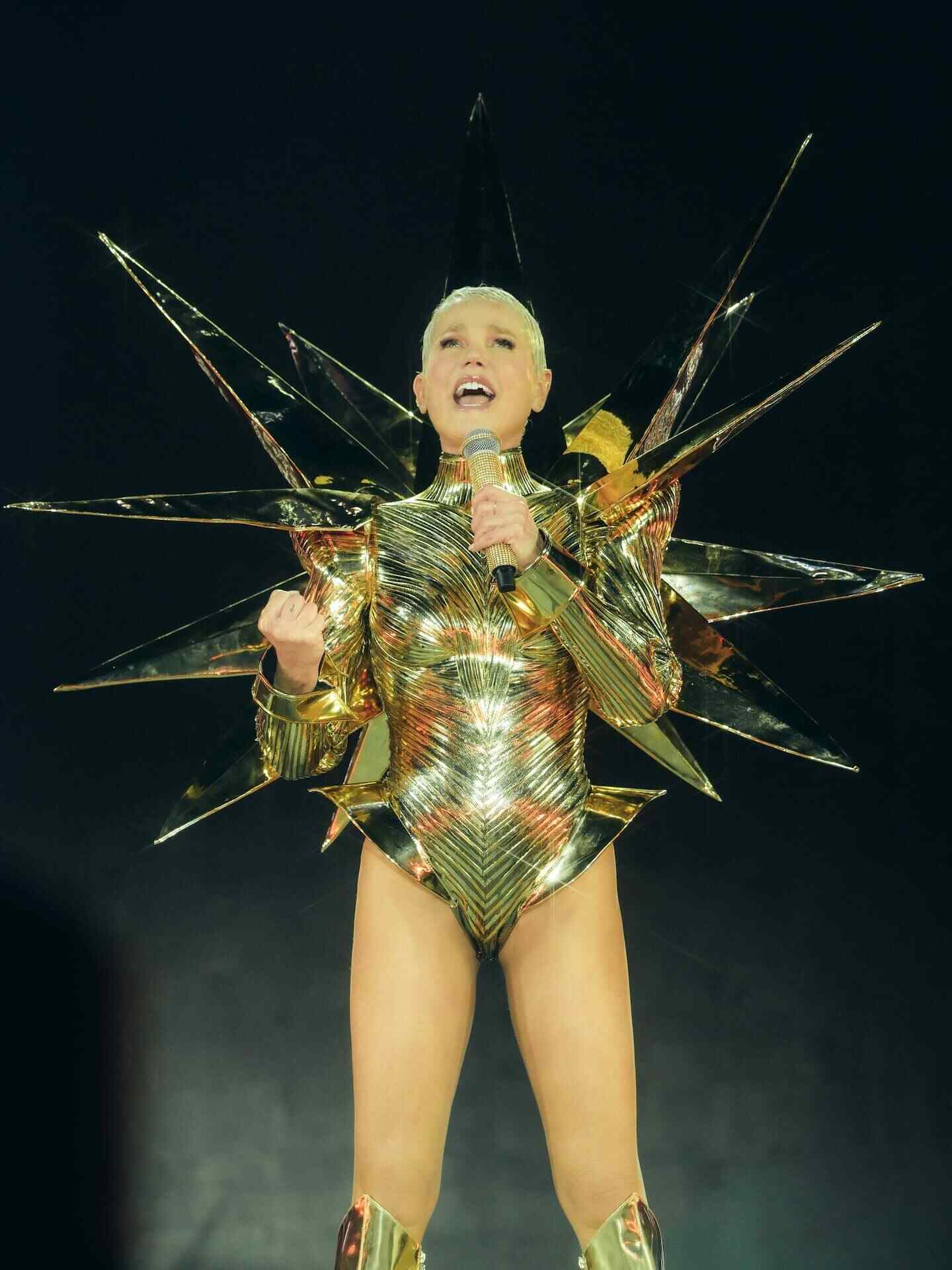 Xuxa Meneghel en su gira de despedida, luciendo un traje dorado con detalles futuristas y brillantes
